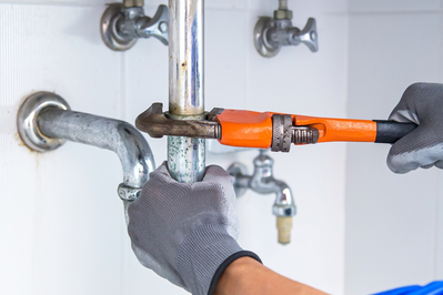 using wrench to tighten pipe connection under sink