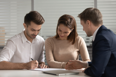 couple signing purchase agreement across from real estate agent