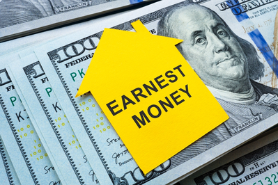 house-shaped note with words EARNEST MONEY on stack of hundred dollar bills