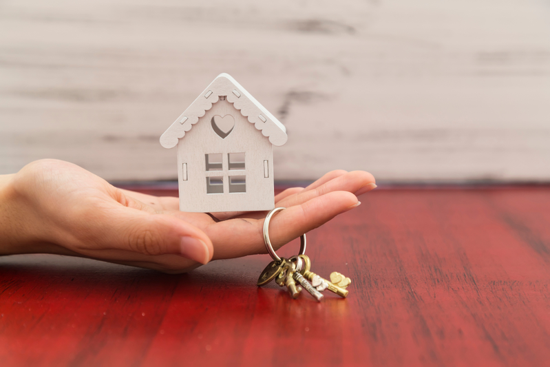 hand holding model of house and set of keys