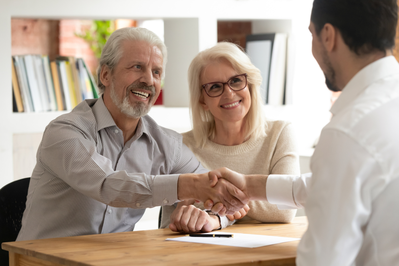 senior couple shaking hands with loan officer