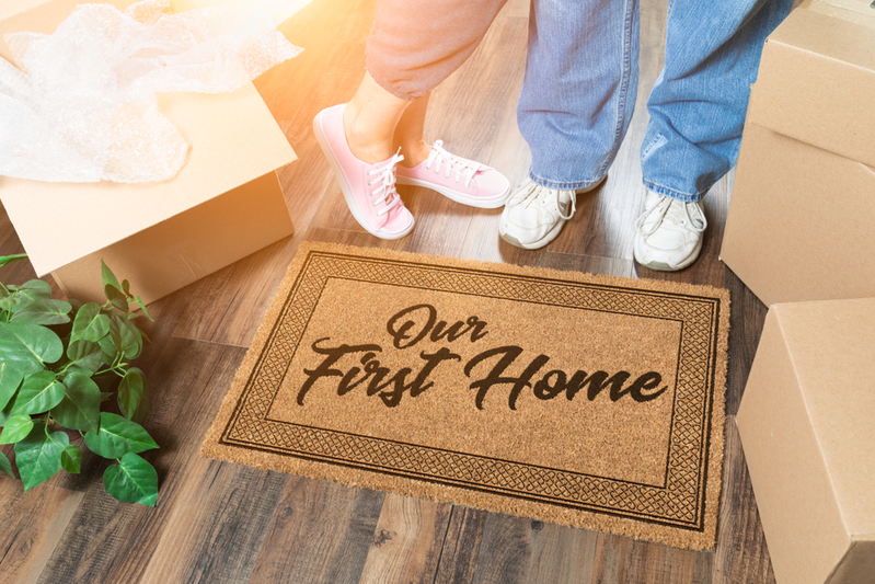 couple standing next to doormat reading Our First Home