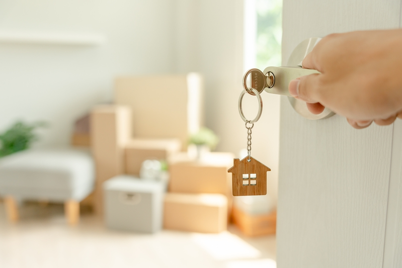 opening door with key with house keychain into new home with moving boxes inside