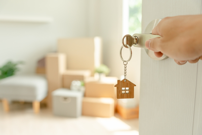opening door with key with house keychain into new home with moving boxes inside