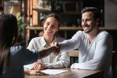young couple meeting with real estate agent and shaking hands
