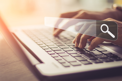 close up of woman's hands using laptop to search online