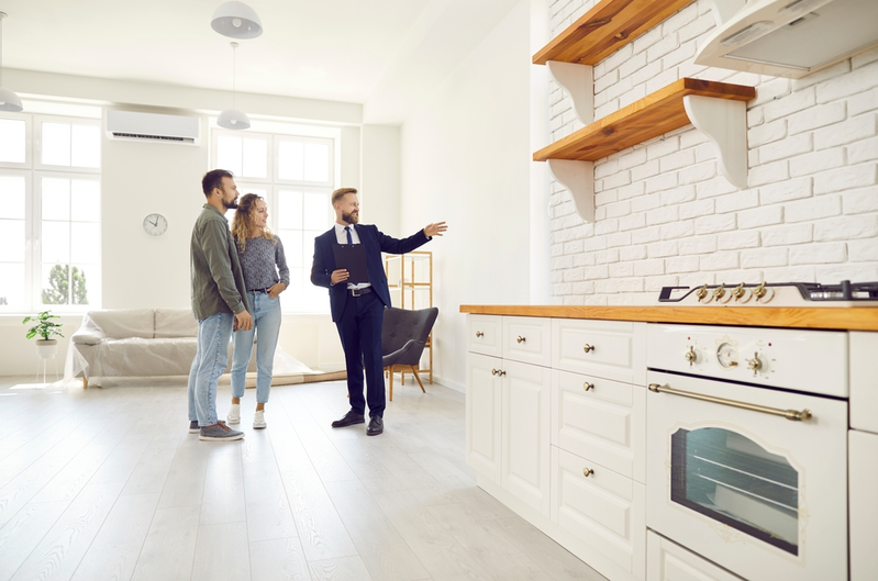 male real estate agent showing couple kitchen in house for sale