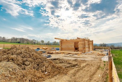 log cabin construction site with mountains in the background