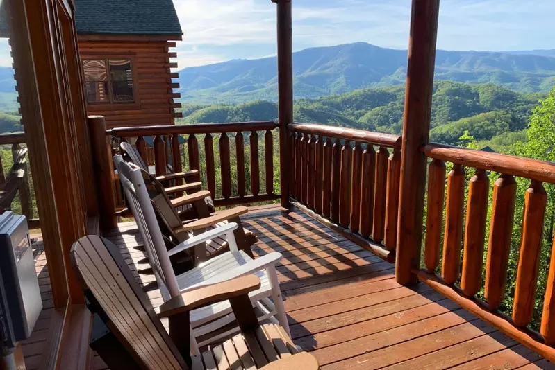 deck of log cabin with chairs facing mountain view