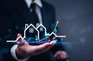 hand holding visualization of houses with upward trending arrows