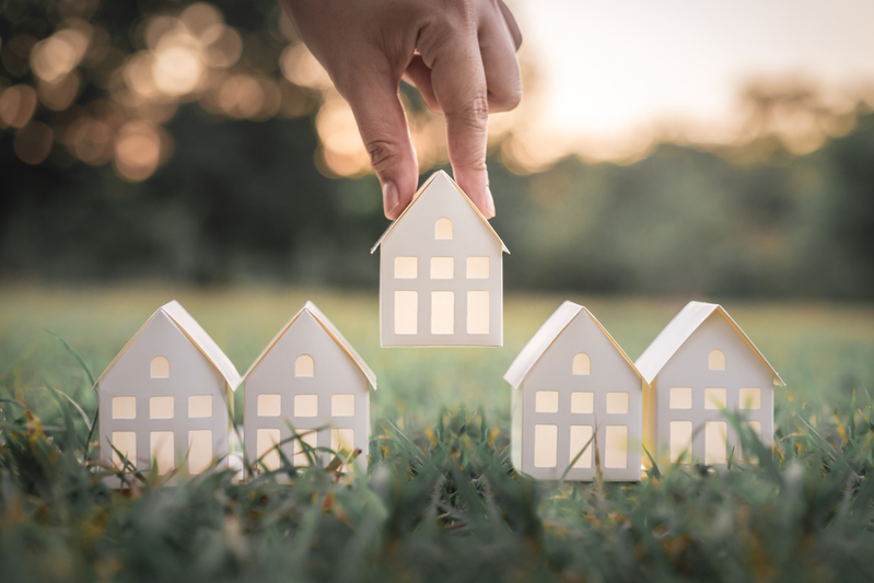 hand choosing white paper house from group