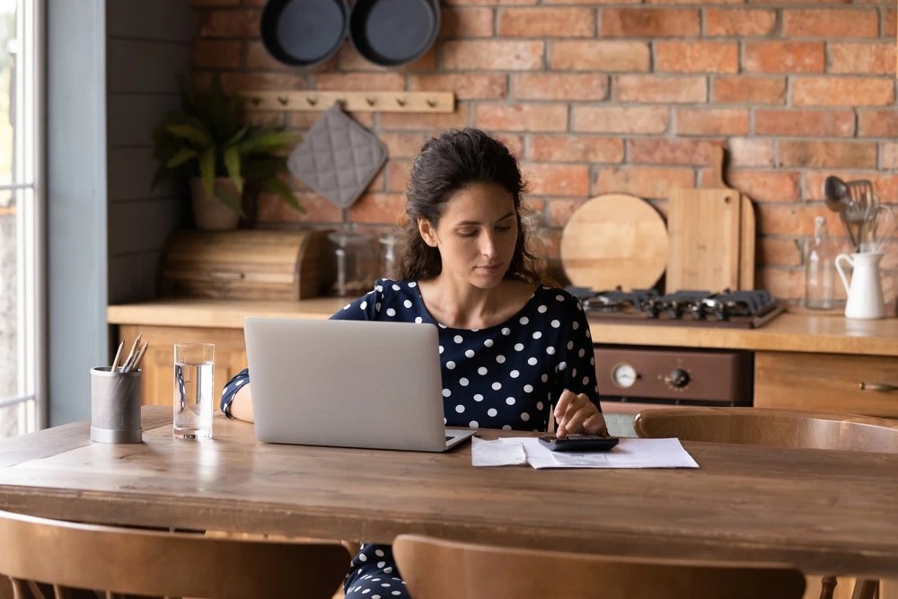investor crunching numbers with calculator and laptop